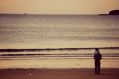 Full length of man standing at beach against clear sky