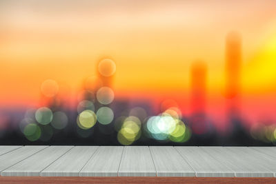 Defocused image of illuminated lights against orange sky