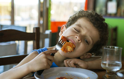 Beautiful curly haired boy eating tortellini in restaurant