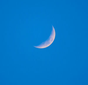 Low angle view of moon in clear blue sky