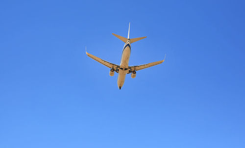 Low angle view of airplane against clear blue sky