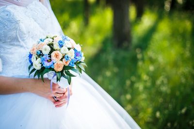 Midsection of bride holding bouquet