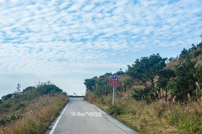 Road amidst trees against sky