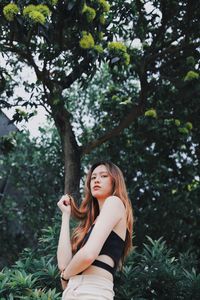 Portrait of young woman standing against trees