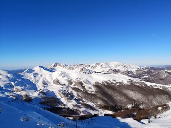 Scenic view of snowcapped mountains against clear blue sky