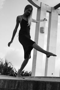 Low angle view of young woman jumping against built structure