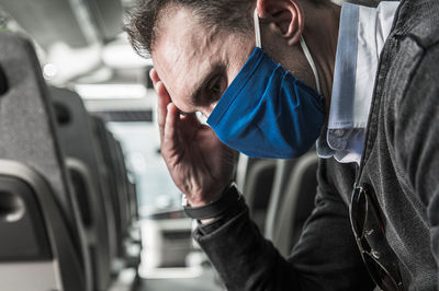 Close-up of man wearing mask sitting in bus