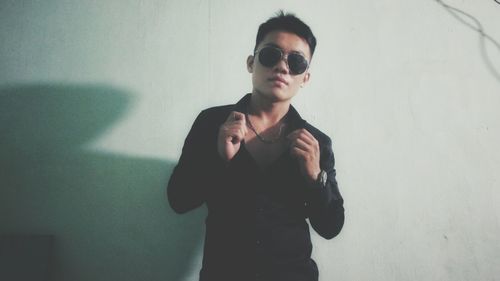 Portrait of young man standing against wall