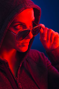 Woman wearing sunglasses in illuminated room