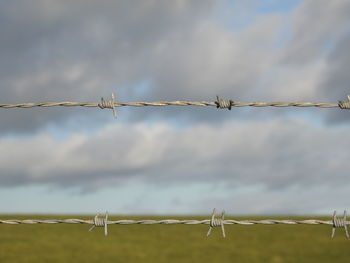 Low angle view of barbed wire against sky