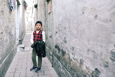 Full length portrait of boy standing on cobblestone