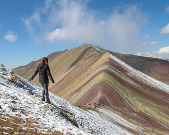 Rear view of man walking on mountain against sky