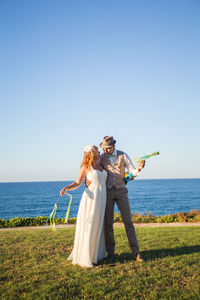 Woman with umbrella on sea shore against sky