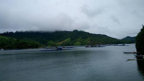 Boats in sea against cloudy sky