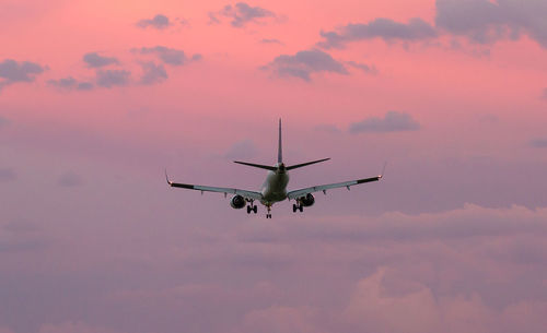 Low angle view of airplane in sky at sunset