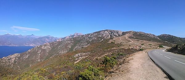 Road by mountains against clear blue sky