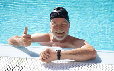 Smiling senior man checking time in swimming pool