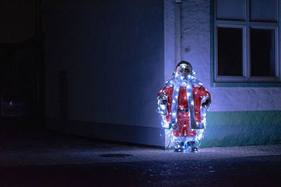 Illuminated santa claus statue on road at night