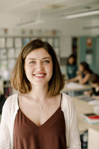 Portrait of smiling female tutor standing in classroom