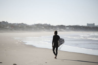 Rear view of man on beach against sky