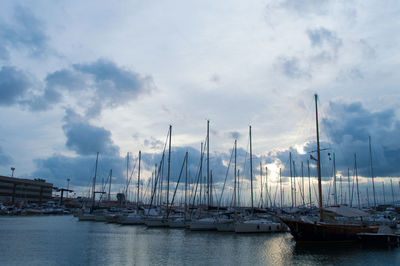 Sailboats moored on harbor against sky