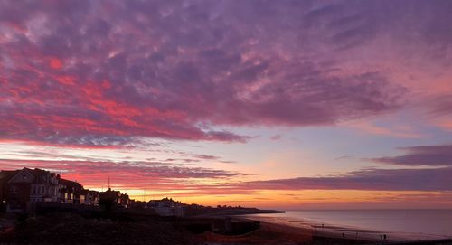 Scenic view of sea against dramatic sky during sunset