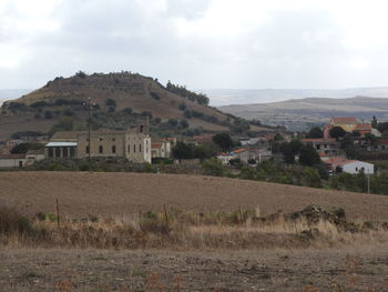 Houses on field by buildings against sky