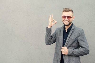Cheerful man gesturing against wall outdoors