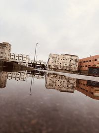 Reflection of buildings in lake against sky in city