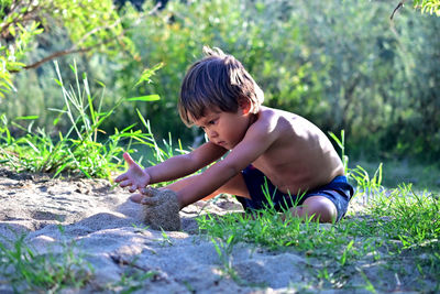 Cute shirtless boy playing at sandy beach