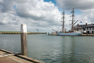 Sailboats on pier by sea against sky