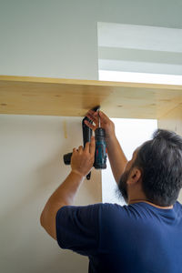 Man using an electrical drill at home. diy, do it yourself, makeover renovation project.