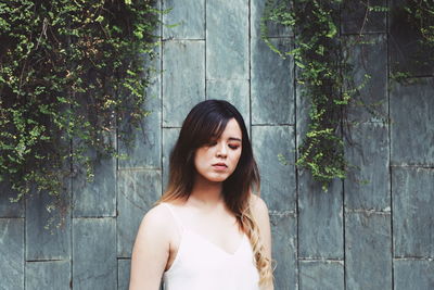 Portrait of a beautiful young woman standing against plants