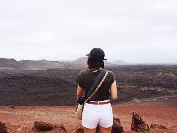 Rear view of woman standing on mountain against sky