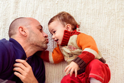 Father with cute daughter lying on floor at home