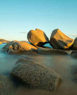 Rocks on beach against clear sky