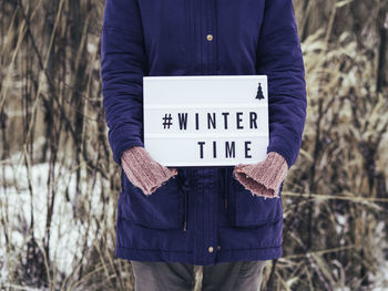 Midsection of person holding placard during winter