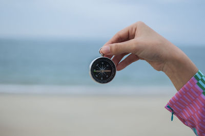 Close-up of hand holding umbrella against sea