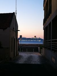 Buildings by sea against clear sky at sunset