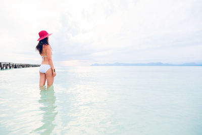 Rear view of young woman in sea against sky