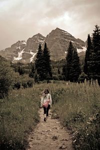 Rear view of woman standing on mountain against sky