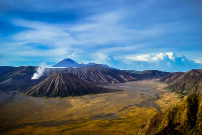 Volcanic crater and landscape against cloudy sky