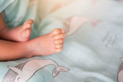 Low section of baby lying on bed