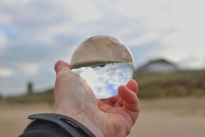 Midsection of person holding glass against sky
