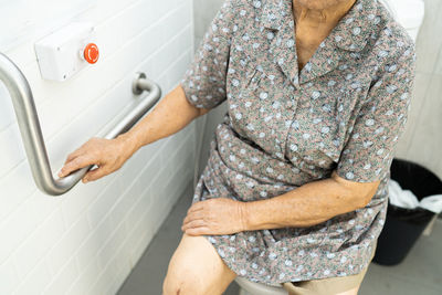 Midsection of woman holding hands at home