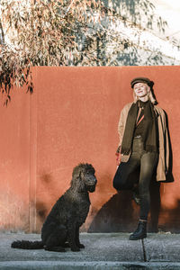 Full length of smiling woman with dog during winter