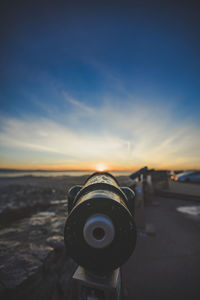 Close-up of coin-operated binoculars at beach against sky during sunset