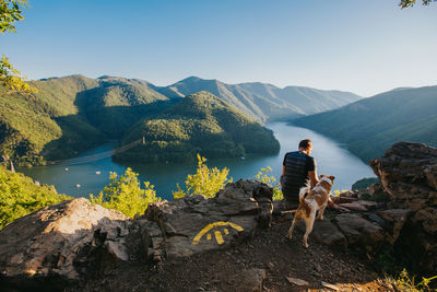 Rear view of man looking at mountains against sky