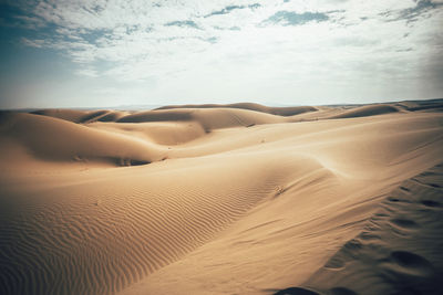 Sand dunes in desert against sky