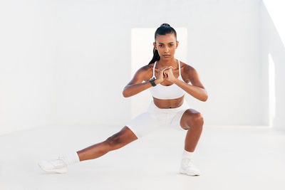 Portrait of young woman exercising against white background